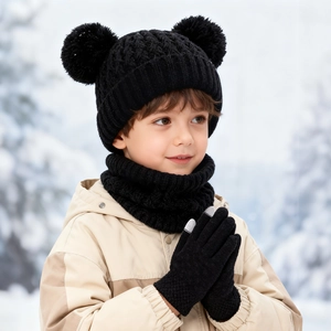 Close-up of kids black knit beanie with double pom-poms, matching scarf and gloves set