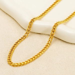 Polished gold cuban link chain necklace in stainless steel on white ceramic background