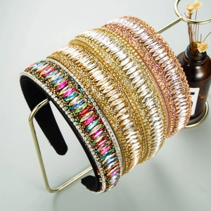 Dettaglio di quattro cerchietti boho con strass e perline colorate su un supporto dorato