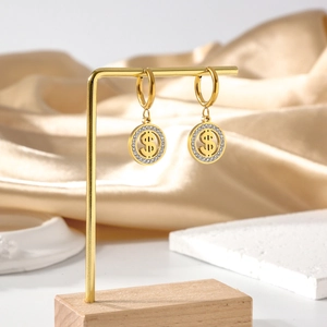 Gros plan de boucles d'oreilles créoles dorées en acier avec un pendentif dollar serti