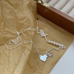 Detail view of 925 silver necklace with heart charms and pearls on a craft paper background