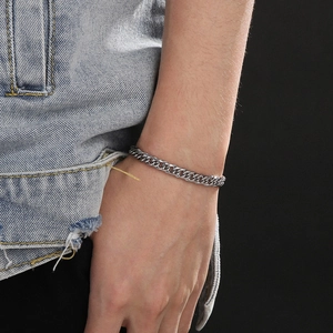 Gros plan d'un bracelet gourmette argenté punk sur poignet avec style veste en jean