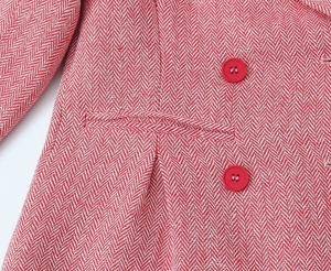 Detail of red and white herringbone fabric with matching red buttons and pocket stitching