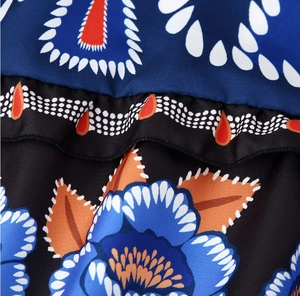 Macro shot of dark blue fabric with orange leaves and white teardrop floral patterns