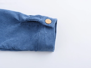 Close-up of blue corduroy sleeve with textured fabric and embossed gold metal button