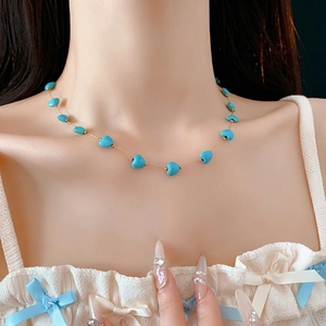 Bohemian gold chain necklace with heart turquoise beads on female collarbone