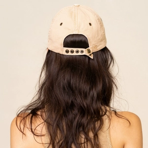 Detail of adjustable metal snap closure on a khaki canvas baseball cap with distressed finish