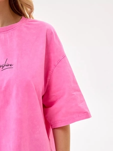 Detail von Sunshine-Buchstabenaufdruck und überschnittener Schulternaht am rosa Baumwoll-T-Shirt