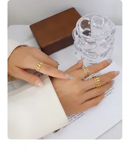 Detalle de tres anillos dorados calados con diseño de cadena lucidos por una modelo