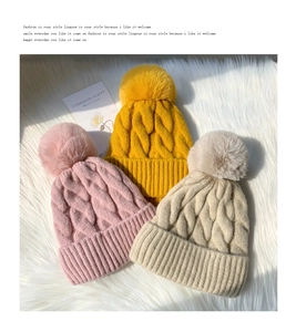 Detailed view of warm knit beanies in pink, yellow, and beige with soft faux fur pom-poms