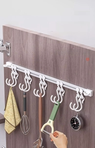 Detail view of a white sliding kitchen rail with 5 hooks mounted inside a dark cabinet door
