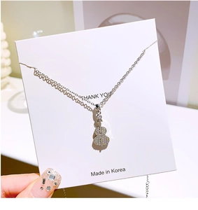 Detail shot of a silver violin pendant necklace with sparkling pavé zircon stones