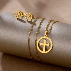 Close-up of golden stainless steel necklace and stud earrings set with hollow cross design
