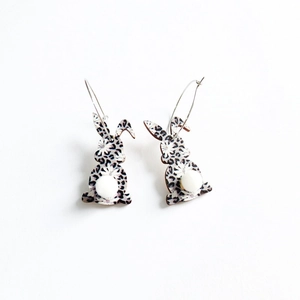 Detail of leopard print bunny earrings with fluffy white pom pom tails and gold hoops