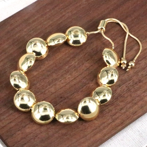 Bracciale a sfere dorate stile francese con chiusura regolabile su legno rustico