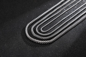 Macro shot of silver stainless steel flat snake chains in various widths on black background