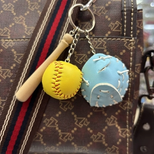 Detailed close-up of mini baseball glove, yellow ball and wooden bat keychain accessory