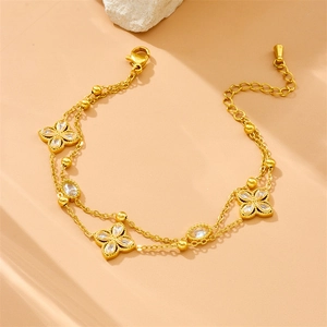 Gold double-layered stainless steel bracelet with zircon clover charms on a warm background