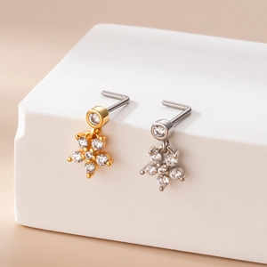 Close-up of gold and silver L-shaped nose studs with sparkling zircon flower designs