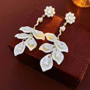Close-up of elegant flower petal earrings with pearl tassels on a vintage leather box