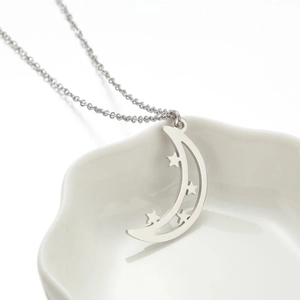 Chic silver star and moon pendant necklace displayed on a white ceramic plate