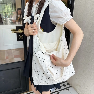Detailed side view of polka dot canvas tote showing interior pocket and shoulder strap