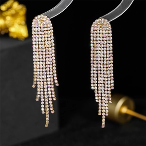 Close-up of luxury gold long tassel earrings with sparkling rhinestones on dark background