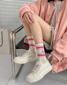 Detail of pink striped cotton socks with bear embroidery and white sneakers