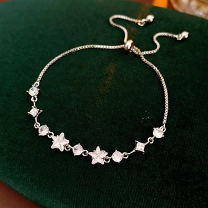 Detail of adjustable silver star and round zircon bracelet on dark green velvet box
