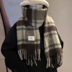 Brown and light blue plaid scarf with fringe tassels shown on a model for a warm winter look