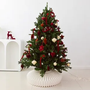 Classic green Christmas tree with burgundy, red, and beige ornaments and honeycomb tree skirt