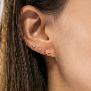 Detail of cute gold octopus and flower stud earrings set worn on a female ear