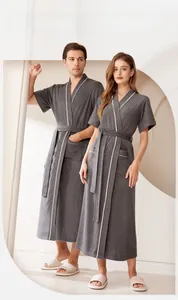 Dettaglio dell'accappatoio grigio scuro assorbente con texture morbida e bordi bianchi