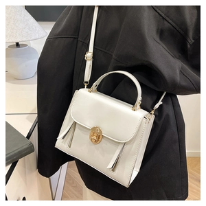 Detailed view of white crossbody bag with gold hardware worn on a black blazer