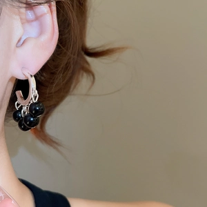Macro view of vintage silver hoops with polished black beads hanging in a tassel style