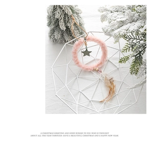 Detailed view of pink plush ring ornament with wooden stars and natural feathers decoration