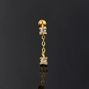 Detail of gold chain earring with round zircons and screw ball back on dark mirror