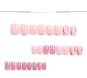Detail view of short square press-on nails in pink tones with marble texture patterns