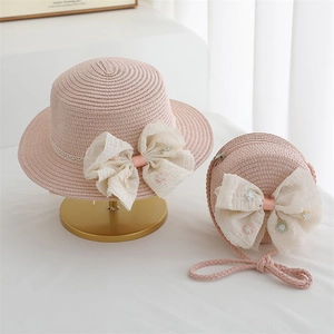 Détail d'un chapeau de paille rose et sac avec nœuds en dentelle et broderie florale