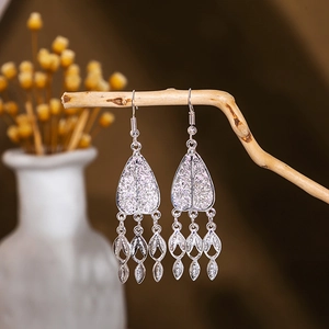 Macro detail of silver vintage ethnic earrings with leaf tassels on a wooden branch