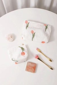 Detailed macro view of two floral tulip jacquard makeup bags with golden flower zippers