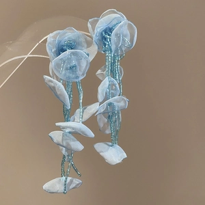 Macro detail of blue chiffon flower earrings with delicate beads and flowing tassels