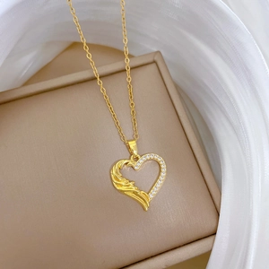 Gold titanium steel heart necklace with wing texture and sparkling crystals on white fabric