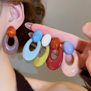 Macro shot of colorful oval acrylic drop earrings showing various resin color options