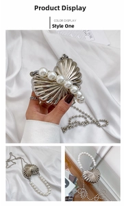 Detailed view of silver heart-shaped evening bag with pearl handle and chain strap