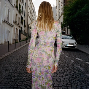Rear view of floral long sleeve slit dress on a cobblestone street in a city
