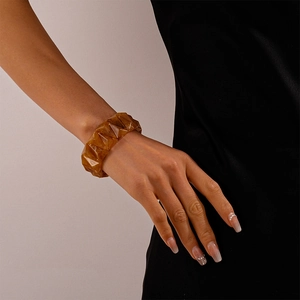 Close-up of amber geometric acrylic bangle showing faceted texture on female wrist