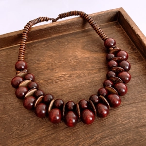 Dettaglio macro di collana in perline di legno e cocco su vassoio scuro