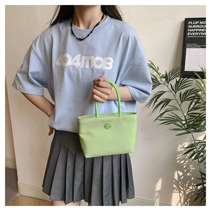 Gros plan du sac seau en nylon vert clair avec logo m circulaire et texture mate