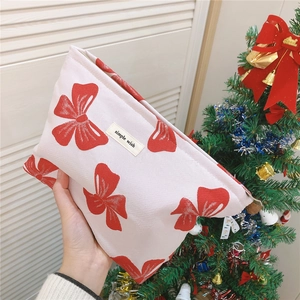 Close-up of canvas makeup bag with red bow print and Simple Wish label on top
